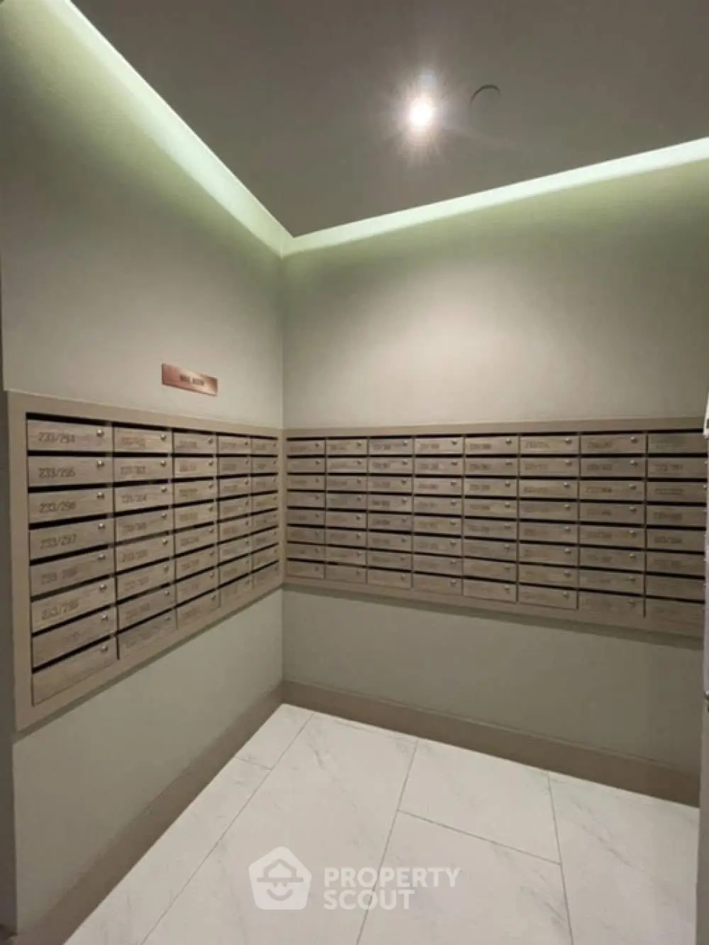 Modern apartment building mailroom with sleek mailboxes and elegant lighting.
