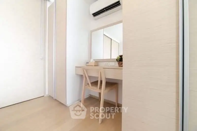 Minimalist study area with wooden desk and chair, featuring a large mirror and air conditioning.