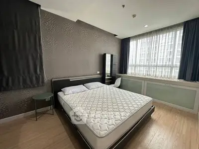 Spacious modern bedroom with large window and stylish decor in urban apartment.