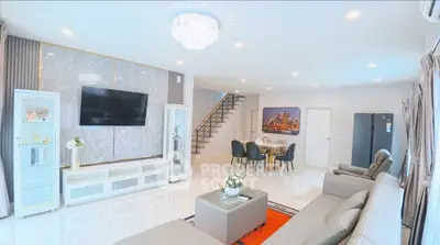 Spacious modern living room with elegant decor and open layout, featuring a large TV and stylish furniture.