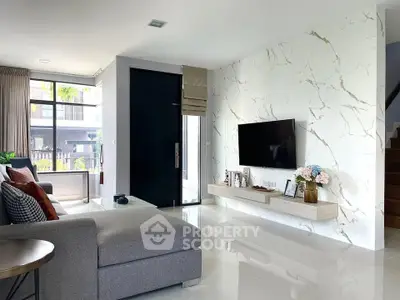 Modern living room with marble accent wall, sleek TV setup, and cozy gray sectional sofa.