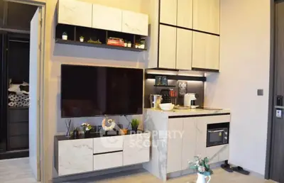 Modern living room with sleek cabinetry and integrated TV unit, featuring stylish decor and a compact kitchen area.
