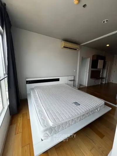 Spacious bedroom with modern design and large window offering natural light.