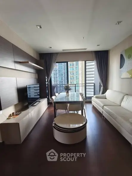 Modern living room with sleek furniture and city view balcony in a high-rise apartment.