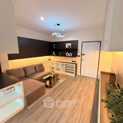 Modern living room with stylish decor and cozy seating area, featuring sleek lighting and wooden flooring.