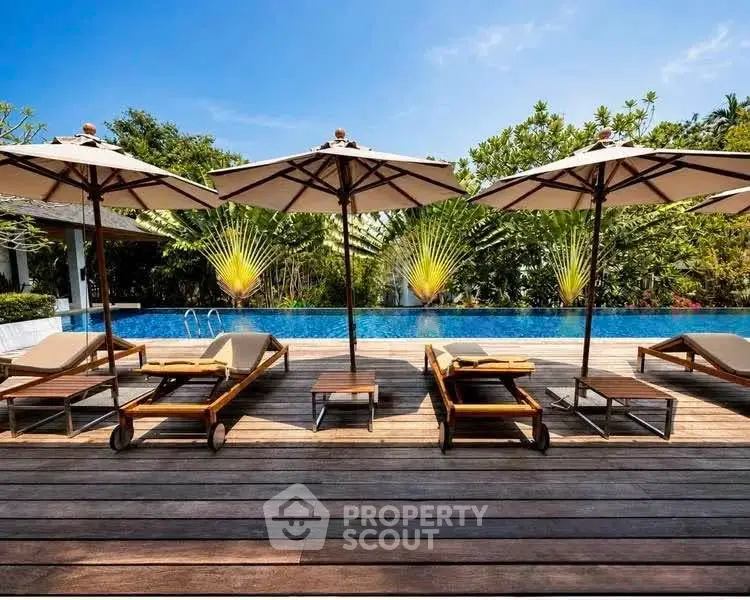 Luxurious poolside area with sun loungers and umbrellas, perfect for relaxation and leisure.