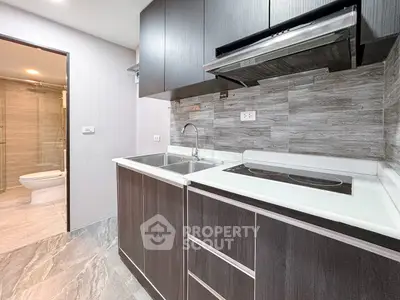 Modern kitchen with sleek cabinetry and adjacent bathroom view