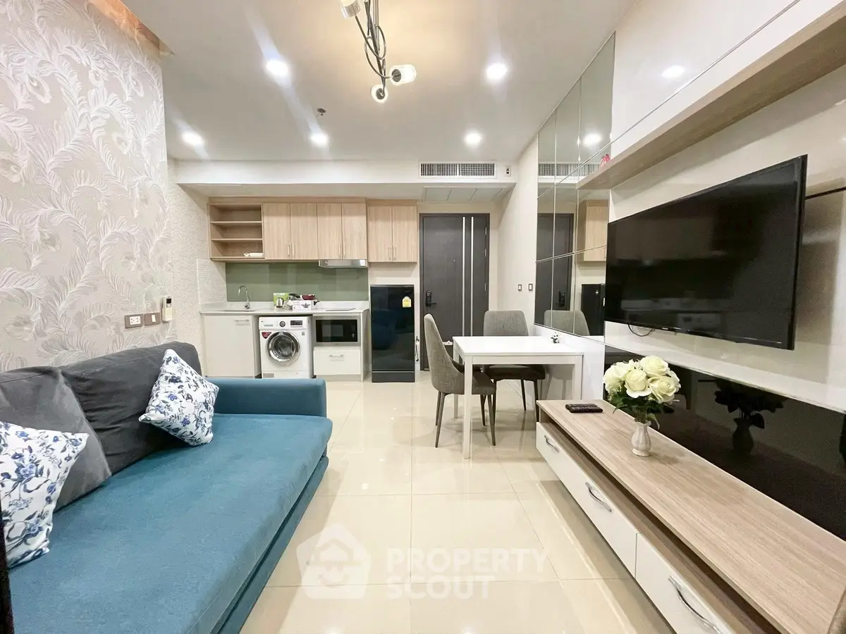 Modern living room with open kitchen, featuring sleek furniture and appliances.