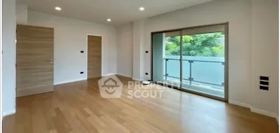 Spacious empty room with wooden flooring and large balcony access.