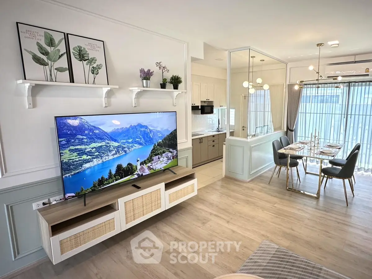 Modern open-plan living room with stylish decor and large TV, adjacent to elegant dining area.