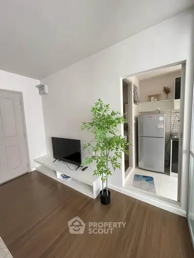 Modern living room with TV and open kitchen featuring sleek appliances and stylish decor.