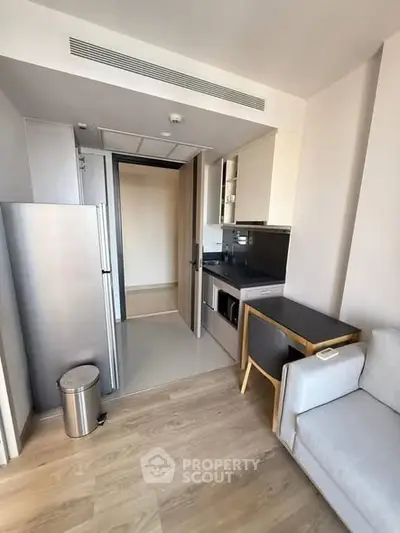 Modern compact kitchen with sleek appliances and cozy dining area in a stylish apartment.