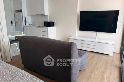 Modern living room with sleek furniture and large TV in a cozy apartment setting.