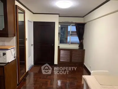 Cozy living room with wooden flooring and modern furnishings in a well-lit apartment.