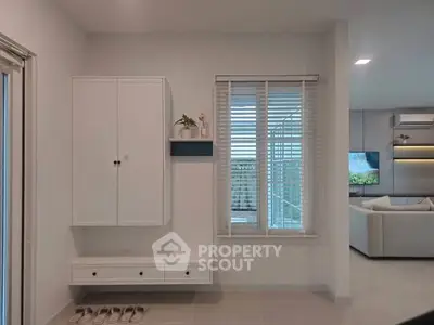 Modern living room with sleek white cabinetry and large window, showcasing a stylish and minimalist design.