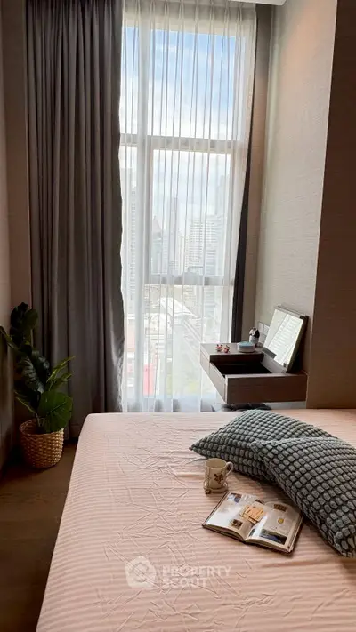 Cozy bedroom with large window offering city view, featuring stylish decor and comfortable bedding.