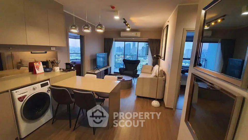 Modern open-plan living room with city view, featuring sleek kitchen and cozy seating area.