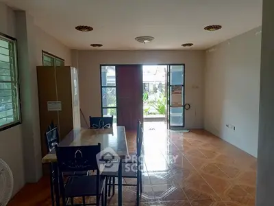 Spacious dining area with natural light and garden view, featuring a wooden table and chairs.