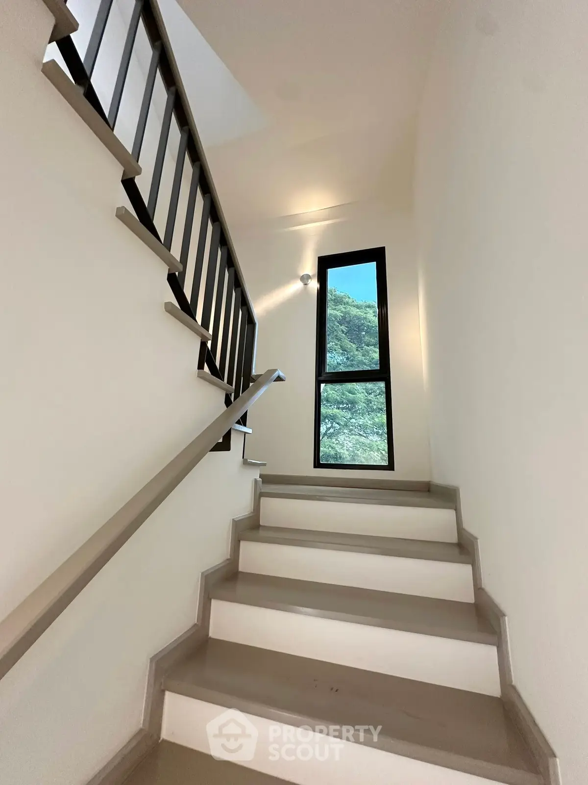 Bright stairway with modern railing and large window offering scenic views.