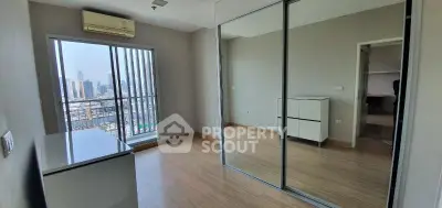 Spacious bedroom with mirrored closet and city view in modern apartment.