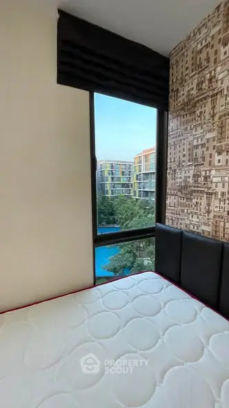 Cozy bedroom with a view of modern apartment complex and pool