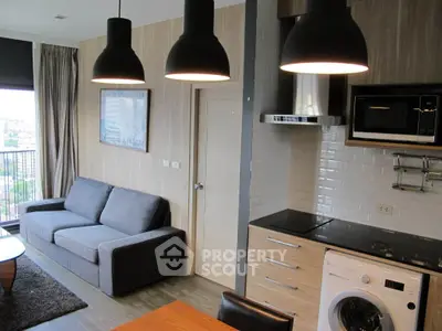 Modern living room with open kitchen, featuring sleek appliances and stylish lighting, perfect for urban living.