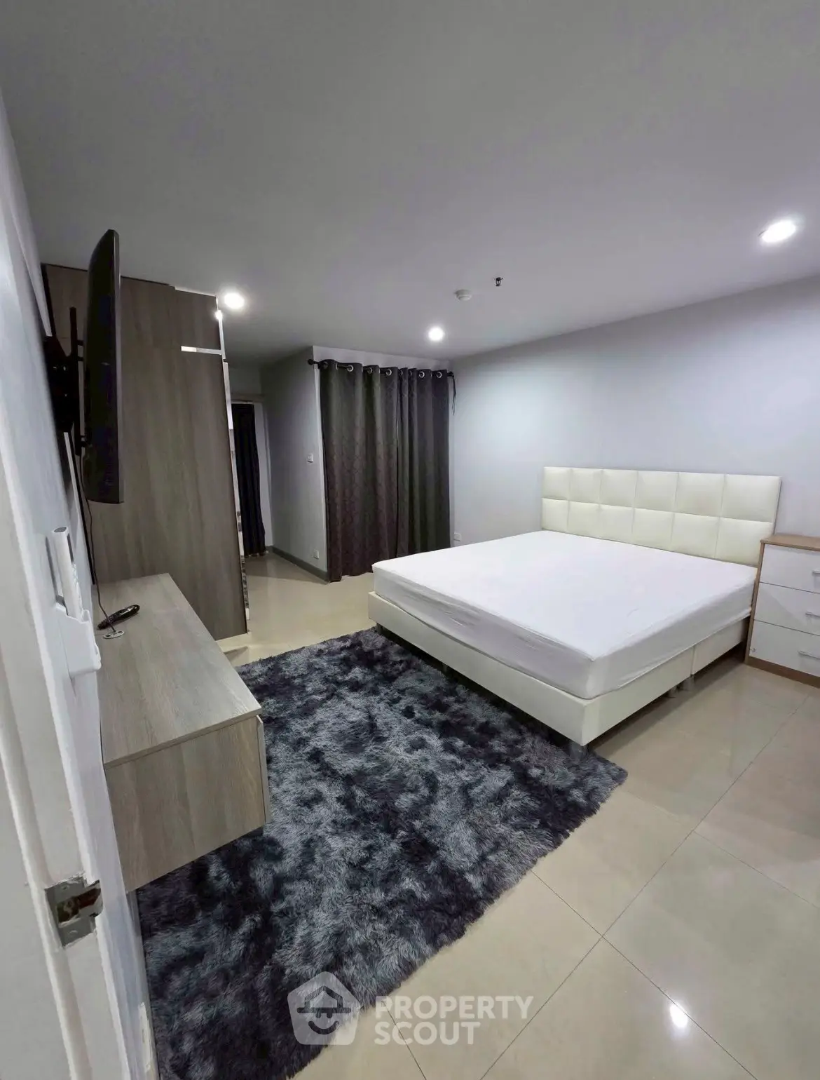 Modern bedroom with sleek design, featuring a plush bed, stylish rug, and ample storage space.