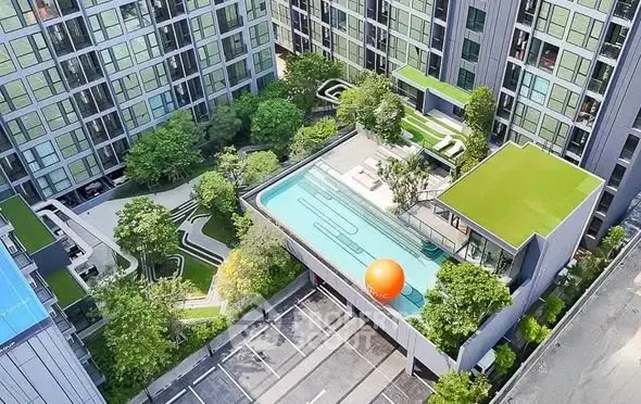 Stunning aerial view of modern apartment complex with rooftop pool and lush gardens.