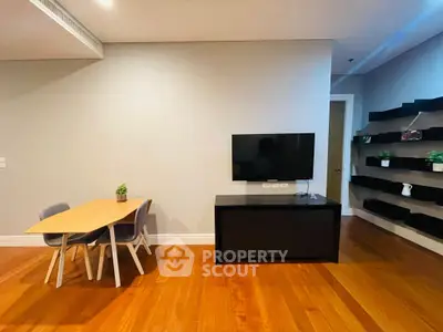 Modern living room with wooden floors, wall-mounted TV, and stylish dining area.