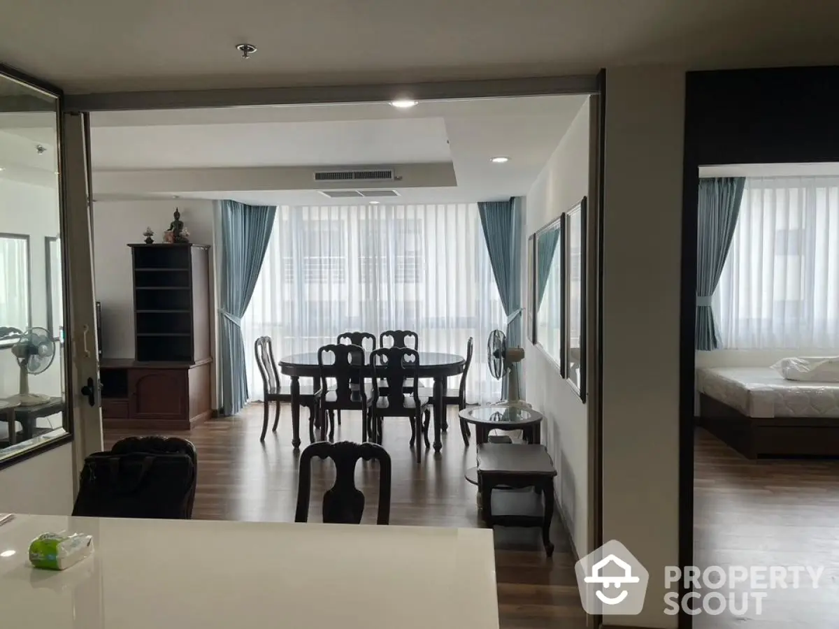 Spacious open-plan living and dining area with elegant wooden furniture and large windows.