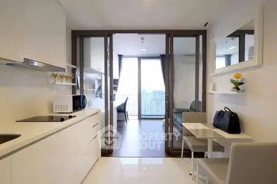 Modern open-layout kitchen and living room with balcony view in a stylish apartment.