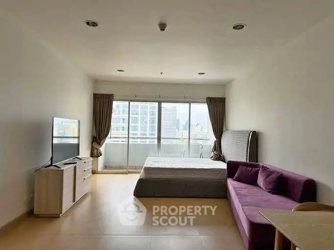Spacious studio apartment with modern furnishings and city view balcony.