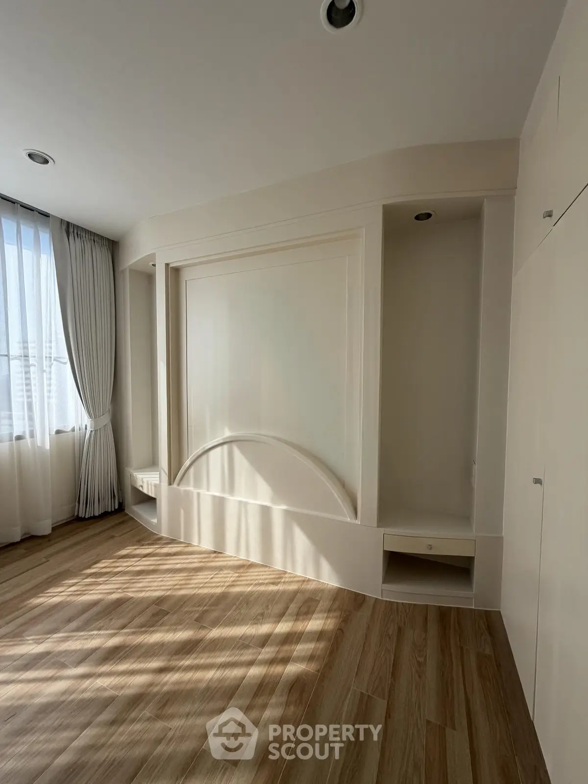 Spacious sunlit room with elegant wood flooring and large windows, perfect for modern living.