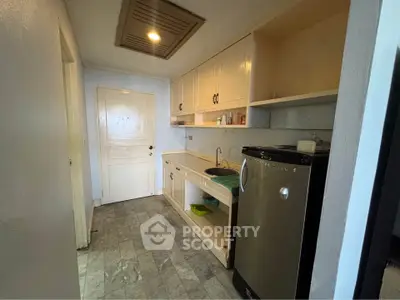 Compact kitchen with stainless steel fridge and marble flooring