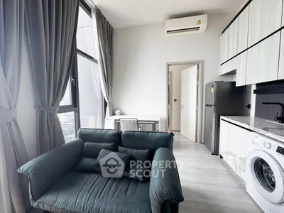 Modern apartment with stylish living room and kitchen featuring a washing machine and sleek design.