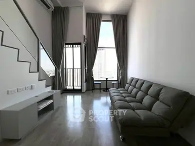 Modern living room with high ceiling and large windows offering city views