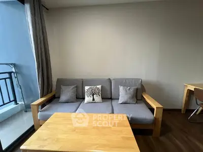 Cozy living room with modern sofa and wooden coffee table, adjacent to a balcony.