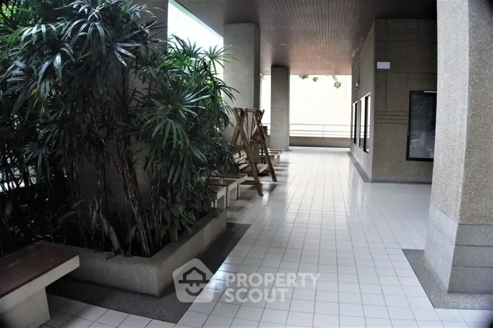 Spacious building entrance with tiled flooring and lush greenery