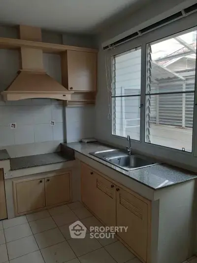 Spacious kitchen with modern cabinetry and large window for natural light.