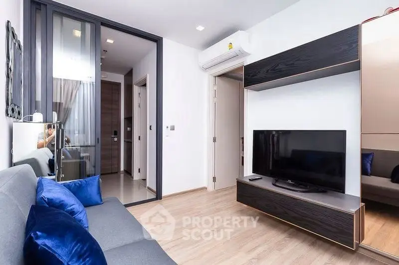 Modern living room with sleek furniture and large TV in a stylish apartment.