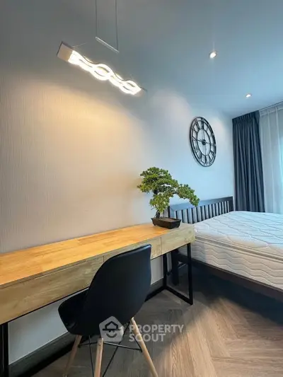 Modern bedroom with stylish desk, chair, and wall clock, featuring elegant lighting and cozy ambiance.