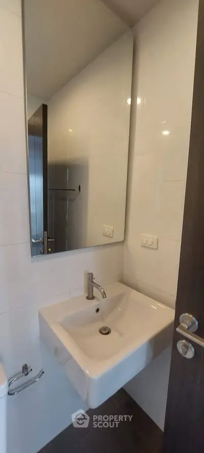 Compact bathroom with modern sink and large mirror, ideal for small spaces.
