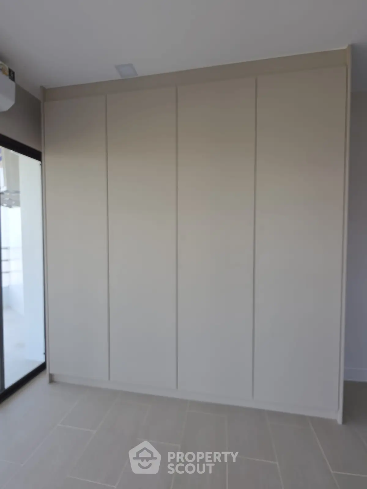 Spacious modern room with built-in wardrobe and large window for natural light.
