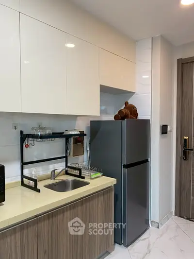 Modern kitchen with sleek cabinets and stainless steel fridge in a stylish apartment.
