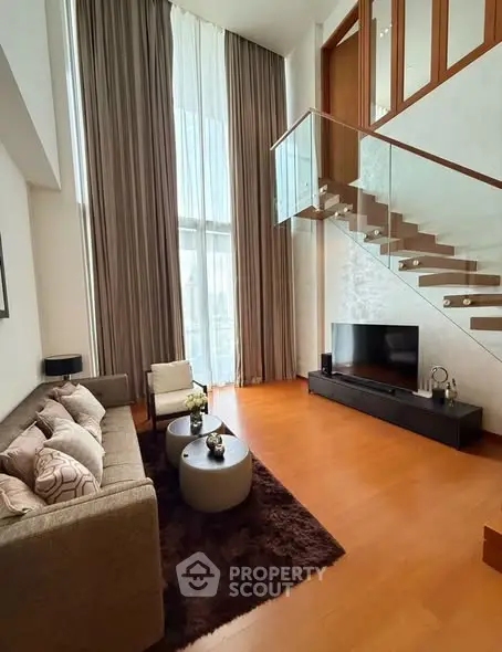 Luxurious living room with high ceilings and modern staircase, perfect for stylish urban living.