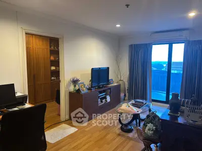 Spacious living room with wooden flooring and large window offering natural light and outdoor view.