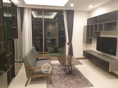 Modern living room with stylish furniture and large glass doors leading to balcony.