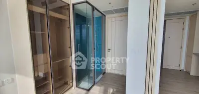 Modern interior with glass shower and wooden flooring, showcasing sleek design and spacious layout.