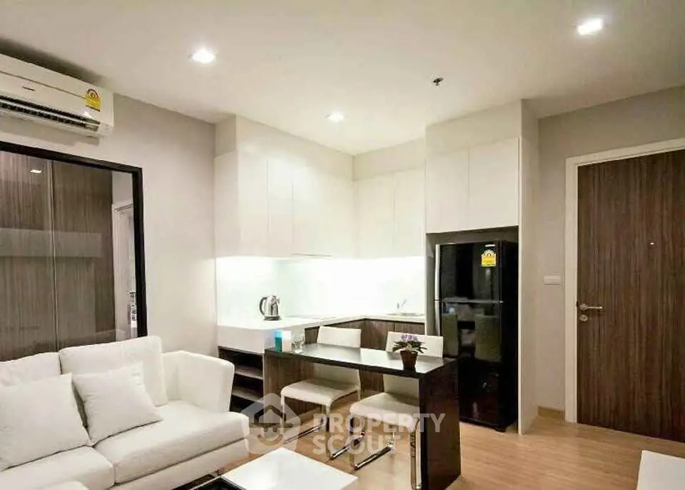 Modern open-layout living room with sleek kitchen and cozy seating area.
