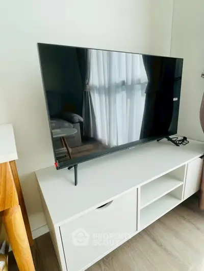 Modern living room with sleek TV on stylish white cabinet and wooden accents.